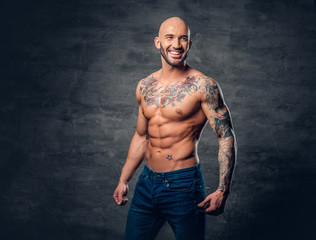 Fototapeta na wymiar Shaved head, muscular male with tattoos on his torso over grey vignette background.
