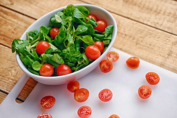 Cutted cherry tomatoes and basil salad on a white plate.