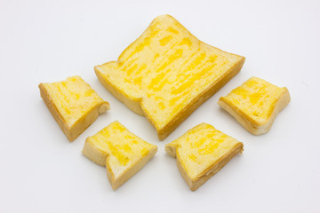 Toast with butter and sugar in a sheet and cut into pieces on a white background.
