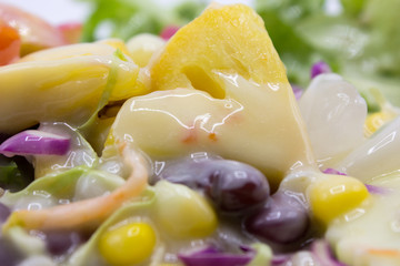 Closeup mixed of fresh salad and fruit. Corn, red beans, pineapple and papaya.