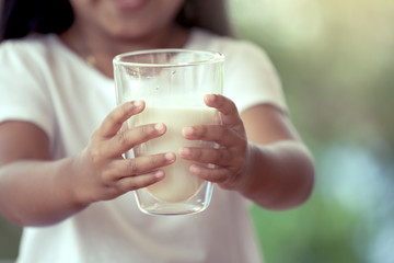 Closeup child hand holding a glass of milk in vintage color tone