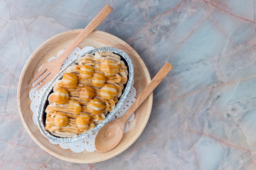 Homemade brownie cake with macadamia and caramel sauce topping. In wooden tray on the table, creamy...