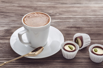 A cup of cappuccino and praline candies.