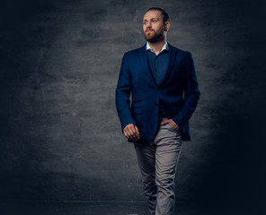 Fototapeta premium A stylish bearded male dressed in a suit and sunglasses over dark grey background.