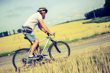 hipster man on a bicycle in the countryside