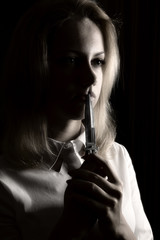 Portrait of young and attractive blond woman close up on black background with knife in her hand.