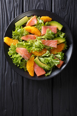 Salad of salmon, oranges, avocado and frisee close-up on a plate. Vertical top view