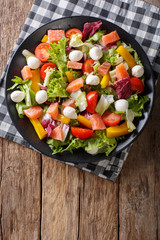 Fresh salad with salted salmon, mozzarella cheese and vegetables close-up. Vertical top view