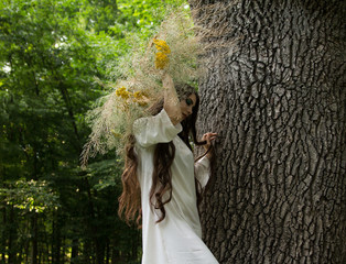 Young girl in wreath walks in forest. Folk style.