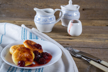 Country or rustic style breakfast. Cottage cheese pancakes with strawberry jam on old wooden table.