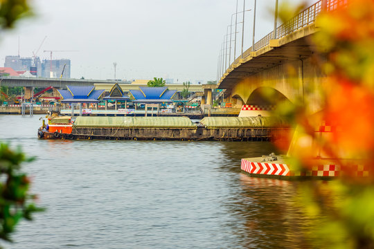 Cargo Ship under road bridge on Chao Phraya river. The one of transportation in Thailand.