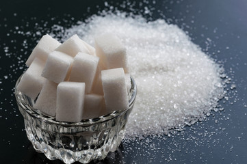white refined sugar and granulated sugar close up on black background