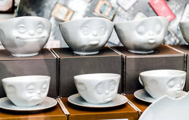 Coffee cups with different smiley emoticons faces, on the showcase