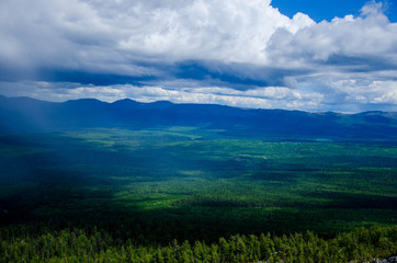Green plain beneath the cloudy skies from the top of mountain