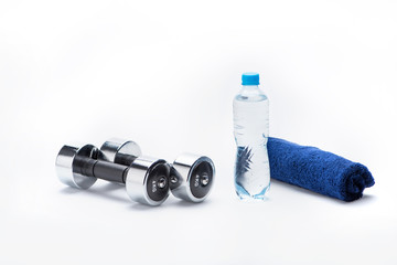 metallic dumbbells, towel and bottle with water isolated on white. equipment sport and healthy living concept