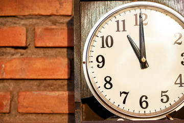 Fototapeta na wymiar It's time! Close up of classic round clock on brick wall.