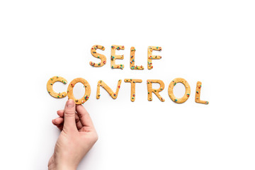 Top view of self control lettering made from sweets and hand holding letter, healthy living concept