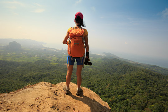 successful woman photographer on mountain peak cliff