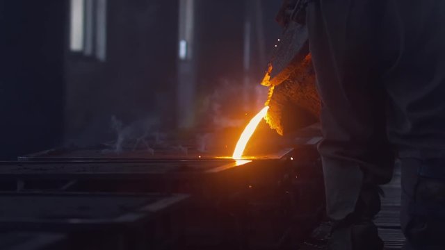 Unrecognizable workers pouring melted metal into the forms at the foundry. HD 120 FPS SLO MO