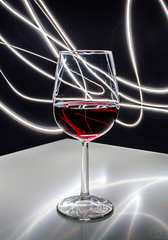 Fototapeta Kieliszek czerwonego wina na białym stole z refleksami świetlnymi w tle  obraz