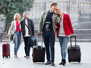 Two couples with baggage sightseeing and smiling