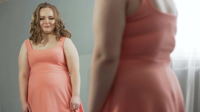 Well-fed girl upset about her mirror reflection, hardly got into favorite dress