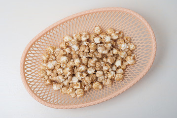 sweet popcorn in a wicker basket on a light background,