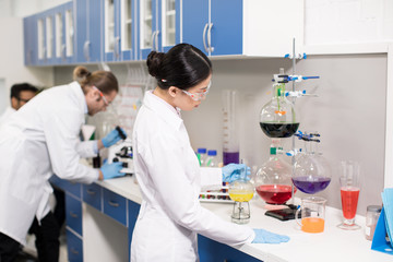 Group of young professional scientists making experiment in research laboratory