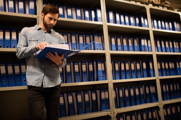 Concerned businessman reading file in storage room