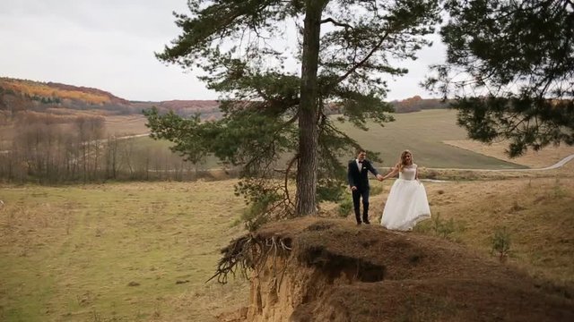 Bride and groom walking on the hill of the mountain. Mountain top