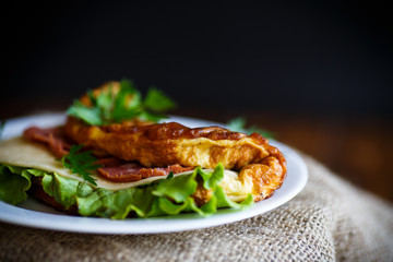 Hot stuffed omelette with cheese, sausage and salad leaves
