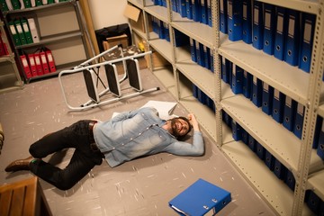 High angle view of fallen businessman and file in storage room 
