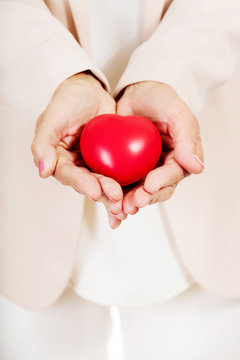 Elderly woman holding heart model on open palms