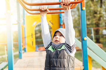 Obraz premium Little boy play on playground with blur park background