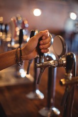 Fototapeta na wymiar Bartender hands using beer tap in pub