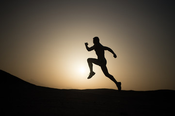 Fototapeta na wymiar man running silhouette at sunset, young caucasian run in mountain