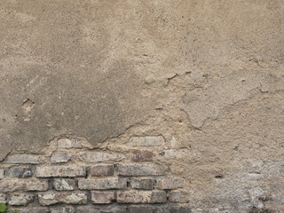 Old decaying brick wall. Background texture of peeled plaster at an old house. Old wall with crags.