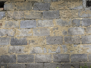 Old decaying brick wall. Background texture of peeled plaster at an old house. Old wall with crags.