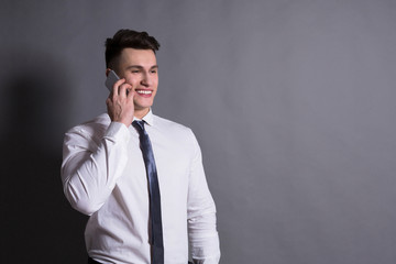 Businessman talking by phone, at gray studio background, copy space