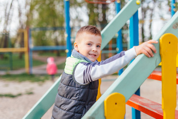Obraz premium Little boy play on playground with blur park background