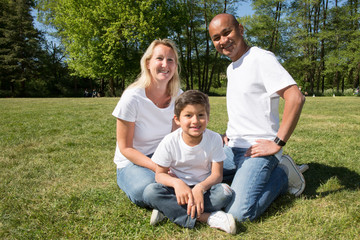 Naklejka na ściany i meble in green grass cheerful family mixed blond and indian with daughter girl
