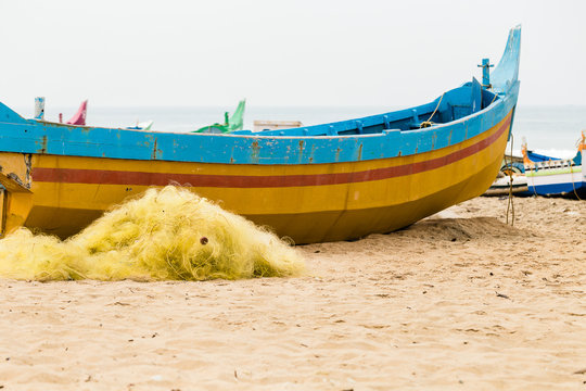 Fishing colorful boat and nets on the beach on a cloudy day.
