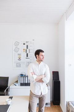 Mid adult man in office arms crossed looking sideways through window
