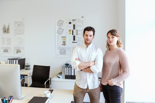 Colleagues in office arms crossed looking at camera