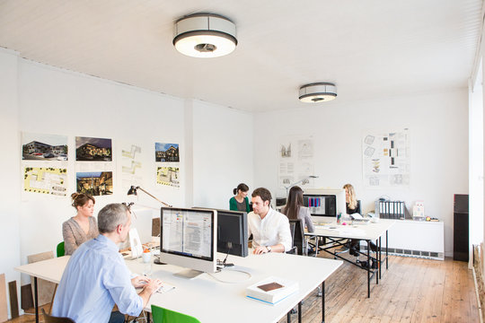 Colleagues in office sitting at desks using computers