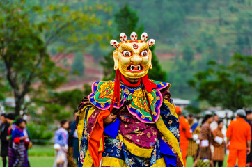 Fototapeta na wymiar Bhutan, masked dancer at a traditional monastery festival the Wangdue Phodrang Tsechu A monk in a colorful dress with mask during the tsechu (dance festival) in Wangdue, Bhutan. 