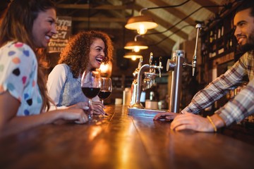 Young women interacting with bartender at counter