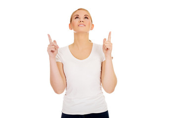 Happy young woman pointing up with both hands 