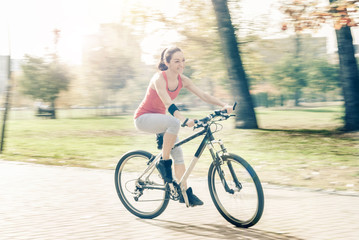Fototapeta premium Carefree woman riding bicycle in park having fun on summer afternoon