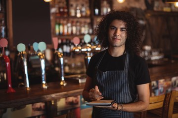 Portrait of young waiter writing on diary